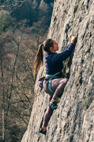 Obraz Woman climbs with steady focus on the grips on the wall.