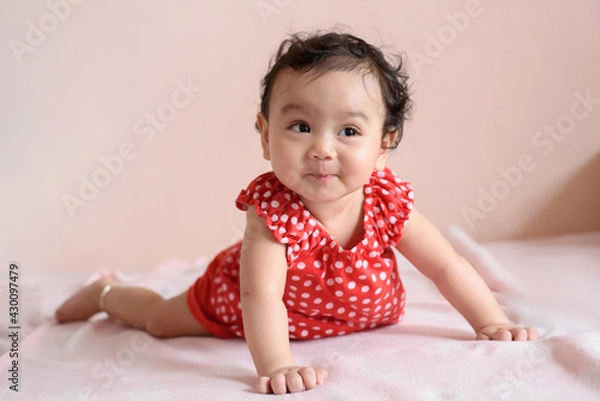 Obraz Portrait of a cute happy little Asian baby girl wearing red dress looking out, baby expression concept