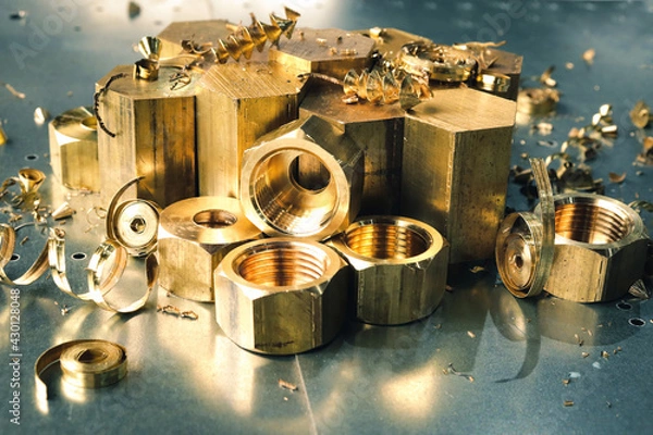 Fototapeta Golden metal parts turned on a lathe in a heavy industry plant. Metalworking of products on cnc machines. 