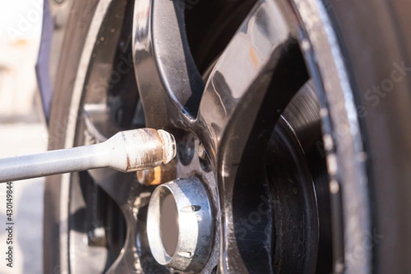 Fototapeta Car wheel replacement. Self-service tire fitting concept. Using a wheel wrench to twist the wheel nuts.