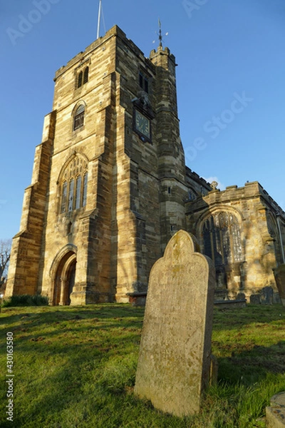 Fototapeta Gravestone in front of the beautiful St Dunstan's Church on a sunny day in Cranbrook, England, Europe
