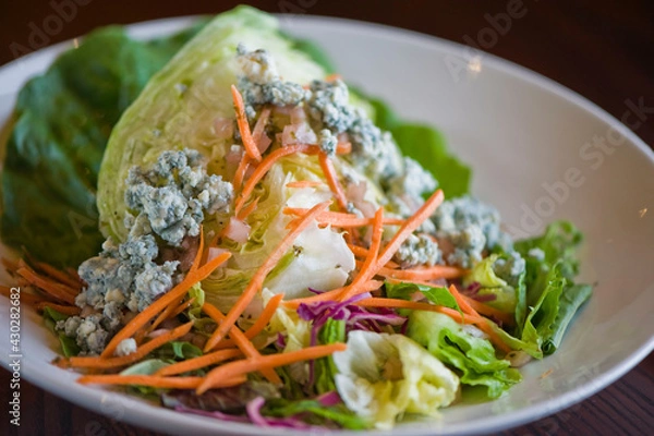 Fototapeta Wedge salad. Classic American salad with iceberg lettuce, blue cheese dressing, red onions, bacon lardons, Parmesan cheese, olive oil, lemon juice, salt and pepper. A Fine dining restaurant classic.