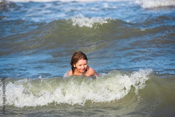 Obraz Happy boy enjoys life on summer beach. Little boy in the spray of waves at sea on a sunny day. Ocean or sea wawes on the background.