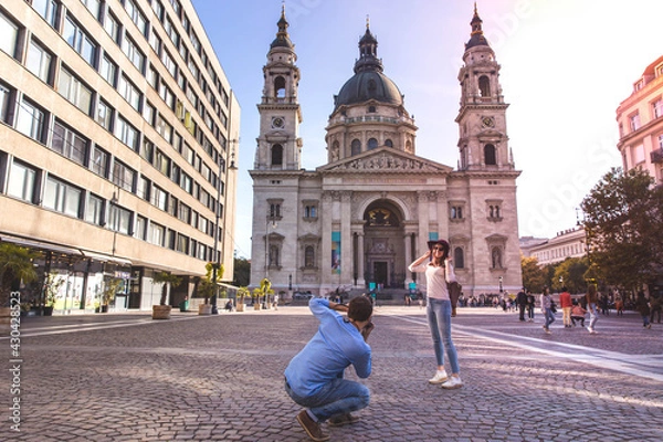 Fototapeta Young couple take pictures of each other while standing in front of St. Stephens Basilica in Budapest.