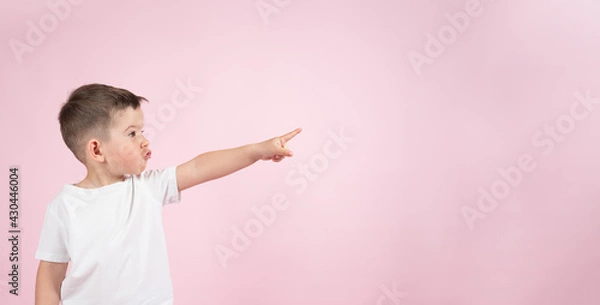 Fototapeta Funny boy pointing up to empty place on pink backgroun, banner for advertising product