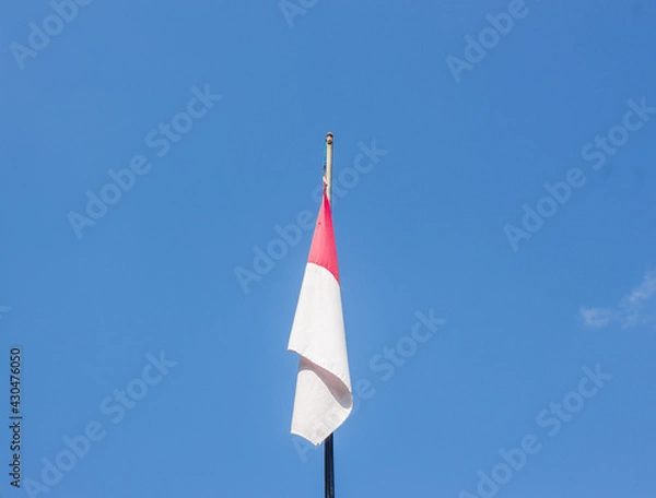 Fototapeta the Indonesian national flag at a high pole with a clear sky.
