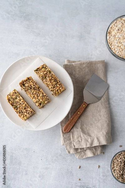 Obraz Overhead view of home made gluten free granola bars on a plate  next to a serving spatula and linen napkin.