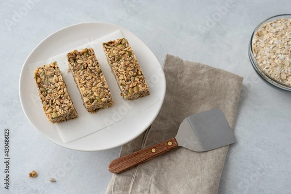 Obraz Home made granola bars on a plate next to a linen napkin and serving spatula.