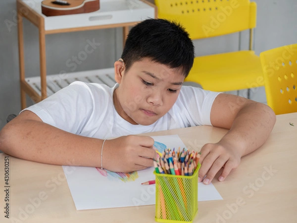 Fototapeta Redundant Children An Asian man is concentrating on coloring wood during art lessons in a classroom for children with disabilities.