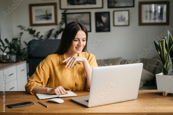 Obraz Head shot pleasant happy young woman freelancer working on computer at home. Attractive businesswoman studying online, using laptop software, web surfing information or shopping in internet store.