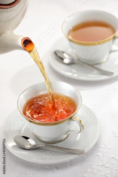 Obraz Pouring tea from the tea pot to the cups