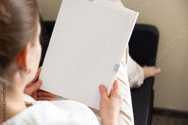 Obraz Hand holds white magazine with blank cover mock up. Hand in shirt hold clear magazine mockup template. A4 book softcover surface design.