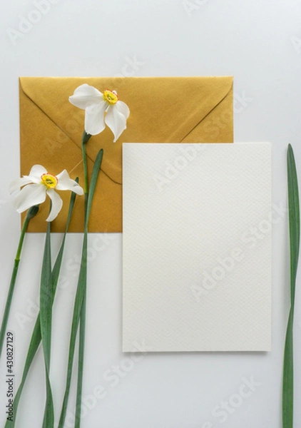 Obraz Mockup card with gold envelope and daffodils, flat lay stationery