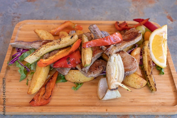 Fototapeta Lamb ribs with vegetables on a wooden plate.