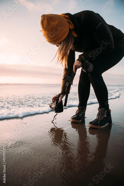 Fototapeta Girl Taking Pictures of the Ocean Waves during the Sunset on the Beach