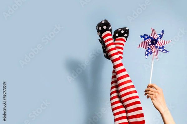 Obraz Female legs in red striped tights over blue background, focus on hand