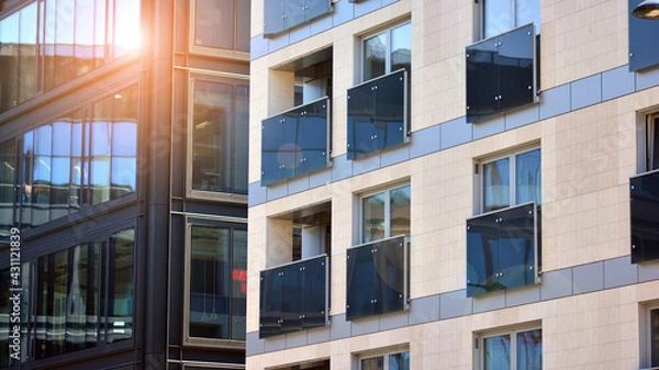 Fototapeta A residential building and an adjacent office building. Modern urban development. Buildings against blue sky and sun light. 