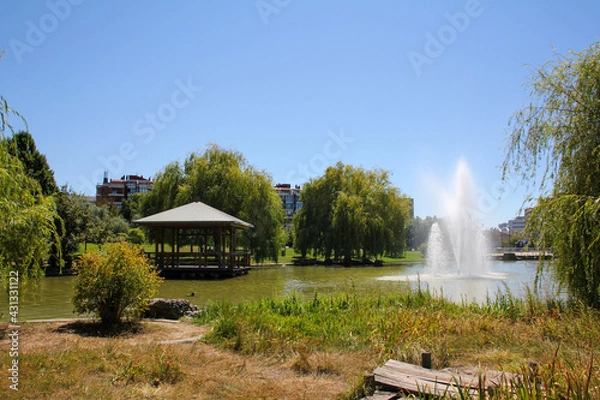 Fototapeta Roundabout and small lake with fountain in the Yamaguchi Park of Pamplona on a sunny day