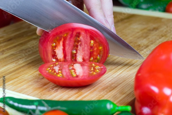 Obraz Chef cuts tomatoes into pieces on a cutting Board