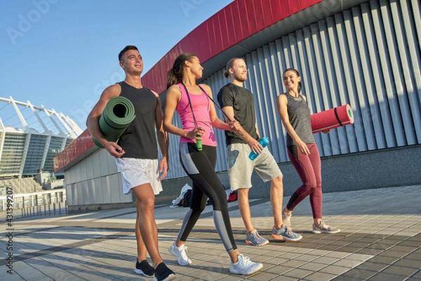 Fototapeta Sportive young people going along paved city square