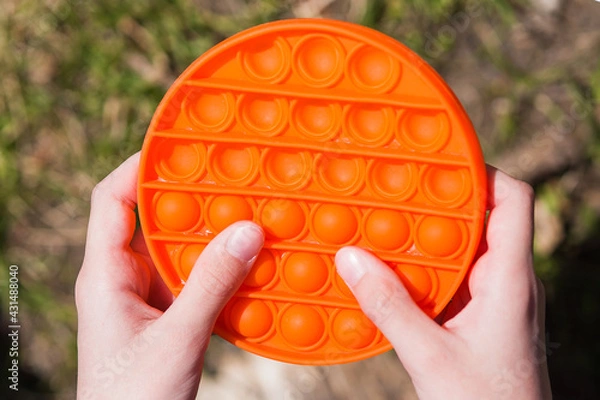 Fototapeta child with colorful poppit game. Close up bunner shot of kid hands playing with colorful pop It fidget toy. Antistress toy
