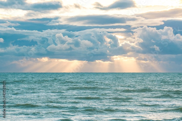 Obraz Sun breaking through the clouds over the sea
