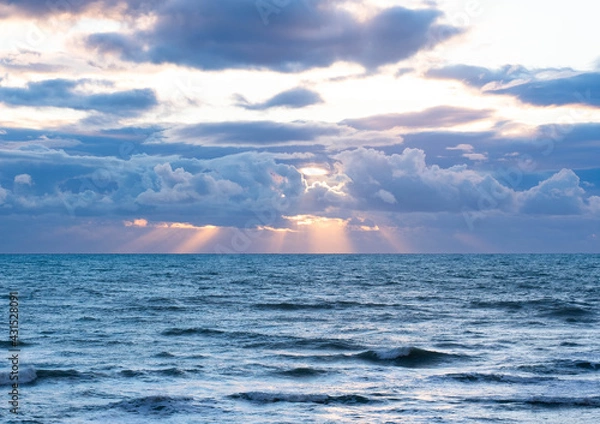 Obraz Sun breaking through the clouds over the sea