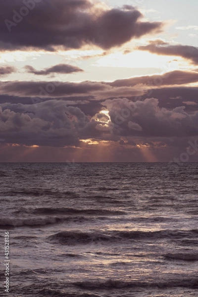 Obraz Sun breaking through the clouds over the sea