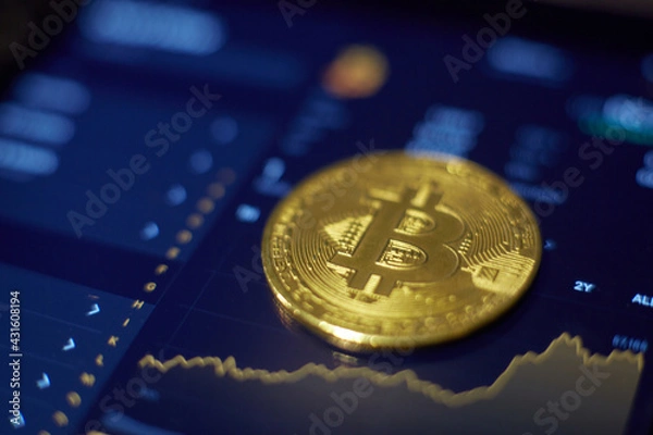 Fototapeta The gold bitcoin coin lies on the tablet screen, which shows cha