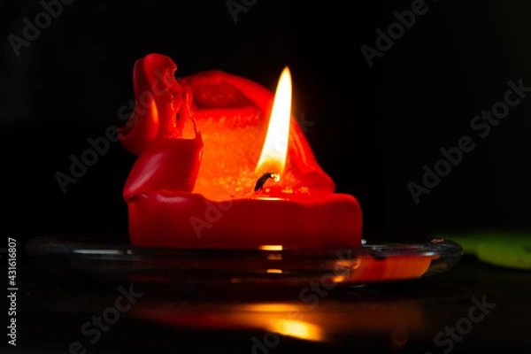 Fototapeta lit candle with red wax over black background