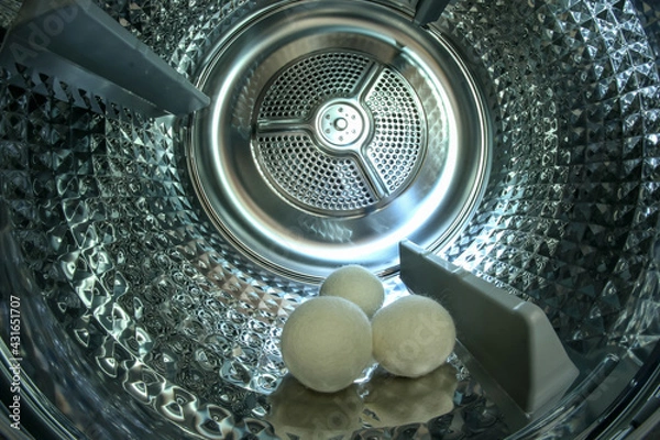 Fototapeta The look inside the shiny metal drum of the modern dryer with three  balls which help to dry the clothing faster. 