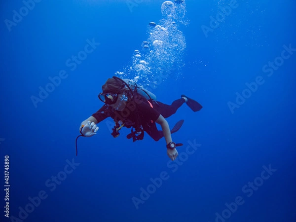 Fototapeta Diver looking at his computer. Clear blue water. Diver with bubbles. Solo Diver. 