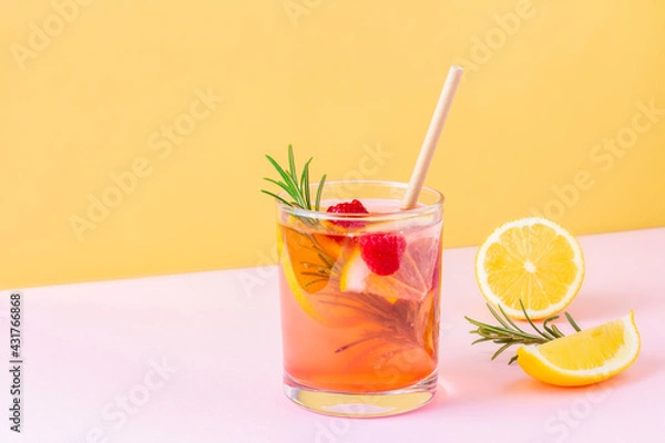 Fototapeta Trendy exotic summer drink with disposable paper straw and rosemary on bicolor background (pink and orange). Fresh fruit lemonade with raspberry for vegans. Copy space