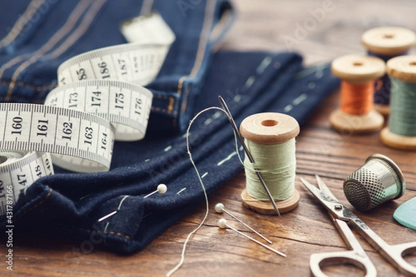 Fototapeta Shortening jeans. Measuring tape, scissors, spools of thread, thimble, including pins and chalk. Jeans cutting.