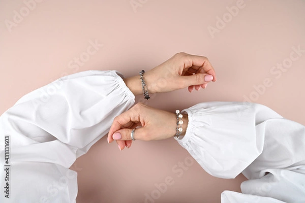 Fototapeta Top view of tender female hands with stylish silver bracelets on pink background.