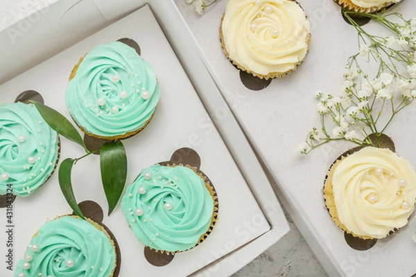 Obraz Boxes with tasty cupcakes and flowers, closeup