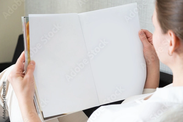 Fototapeta beautiful female hands holding white magazine with blank cover mock up at home