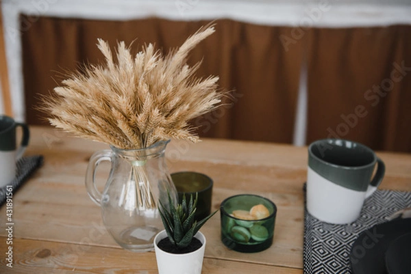 Fototapeta ears of corn in a glass transparent vase on a wooden table in the village