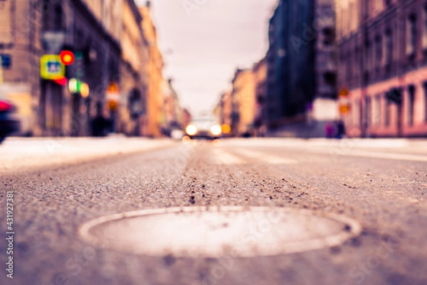 Fototapeta Snowy winter in the big city, the car is a red traffic light. Close up view of a hatch at the level of the asphalt