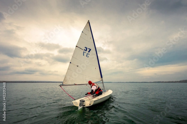 Obraz the yacht floats on the water against the backdrop of the cloudy sky and the sun