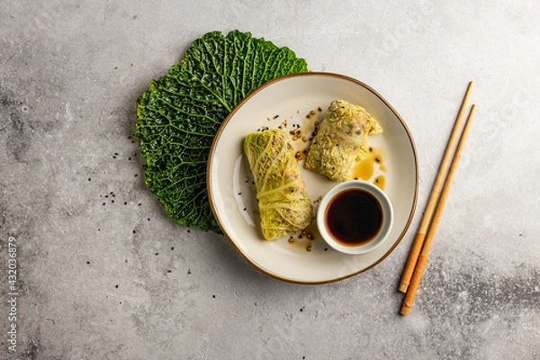 Fototapeta Leaves of Savoy cabbage stuffed with vegetables. Asian cabbage rolls. Vegan. Top view.