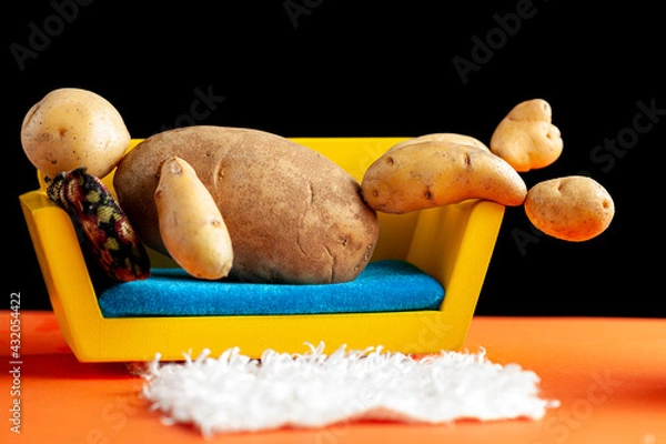 Fototapeta A quirky metaphorical concept image showing a potato man lying on a couch in a living room setting. Image for being couch potato, obesity, sedentary lifestyle and health effects.