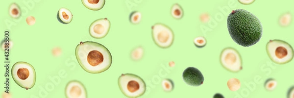 Obraz Creative pattern with flying avocado halves on green background.