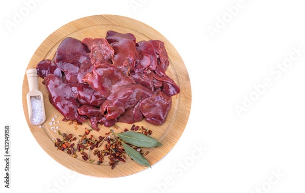 Fototapeta raw chicken or goose liver with spices on a round wooden cutting board close-up isolated on a white background.top view