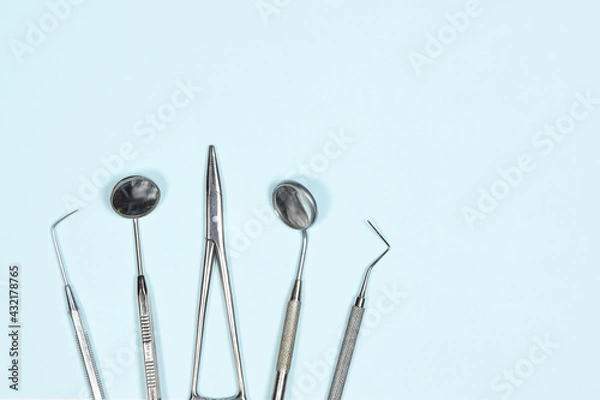 Obraz Medical dental instruments on light blue background with copy space. Flat lay close up top view on dental equipment. dental mirrors, probes, forcepts