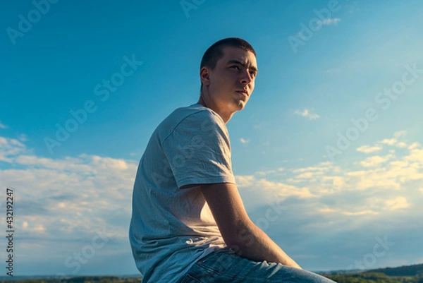 Obraz seated young man looks into the distance in a beautiful landscape