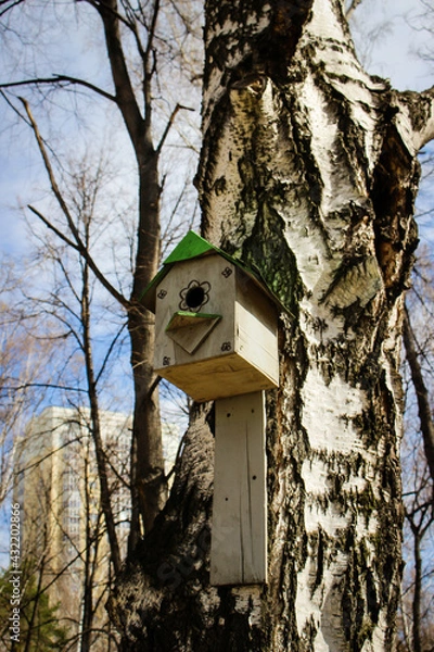 Fototapeta Birdhouse on a tree. Wooden bird house on a tree trunk in a green park outdoors.
