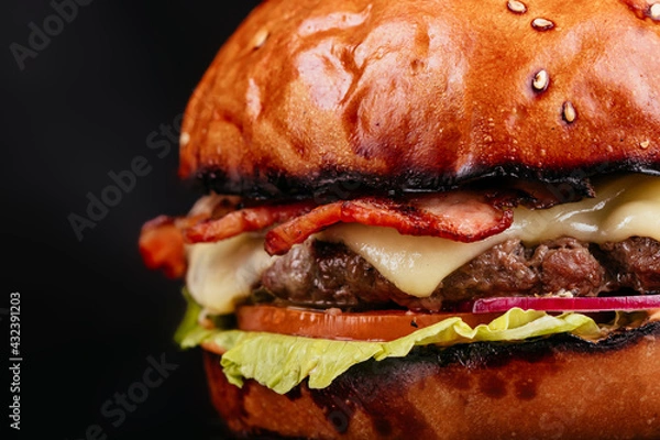 Obraz Juicy and sliced ​​burger with meat cutlet close up. on a black background.