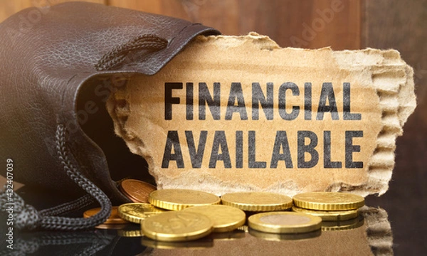 Fototapeta On the table is a bag of money from which sticks out cardboard with the inscription - FINANCIAL AVAILABLE