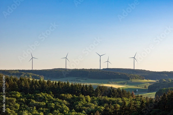Fototapeta wind turbines in green field against blue sky in summer in Germany. alternative sustainable energy for climate change